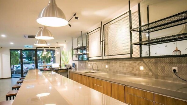 A modern kitchen with a long countertop, pendant lighting, and a view of the outdoors. - Urban Inn, Jitra (Jitra)