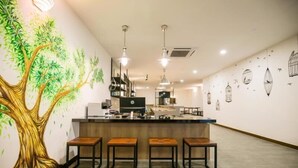 A modern kitchen with a central island, bar stools, pendant lighting, and a mural of a tree on the wall. - Urban Inn, Jitra (Jitra)