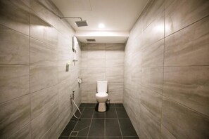 A small, modern bathroom with a toilet, a showerhead, and a towel rack.