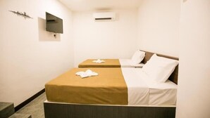 A hotel room with two beds, a flat-screen TV, an air conditioning unit, and a cityscape artwork on the wall. - Urban Inn, Jitra (Jitra)