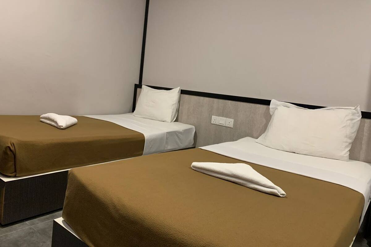 Two single beds with brown bedding and white pillows in a hotel room.