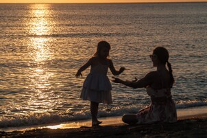 Una playa cerca, arena negra, sillas reclinables de playa, sombrillas