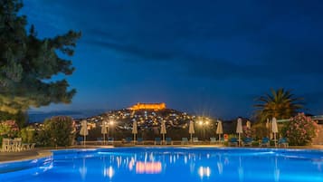 Una piscina al aire libre, sombrillas, sillones reclinables de piscina