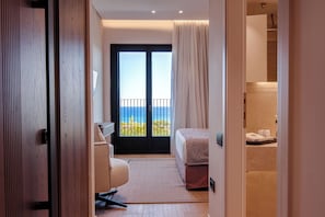 A hotel room with a bed, a desk, a chair, a bathroom, and a balcony with a view. - Hotel Delfinia (Lesvos)