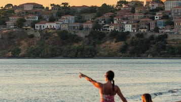 Perto da praia, areia preta, espreguiçadeiras, guarda-sóis