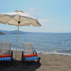 On the beach, black sand, sun-loungers, beach umbrellas