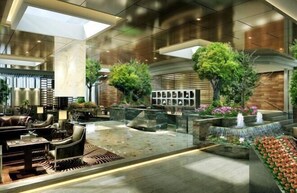 A spacious lobby with a seating area, a water feature, and a wall with framed pictures. - Tiancheng Grand Hotel (Guangyuan City)