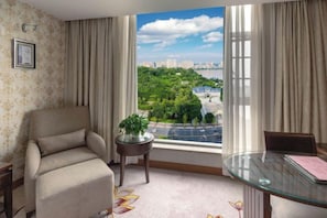 A room with a view of a cityscape, a sofa, a small table with a plant, and a glass table with a chair. - Eyring Daqian International Hotel (Neijiang City)