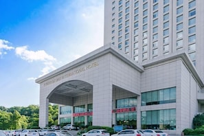 A modern hotel with a prominent entrance, multiple floors, and a parking area.