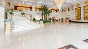 A spacious lobby with a grand staircase, a chandelier, and a reception desk. - Eyring Daqian International Hotel (Neijiang City)