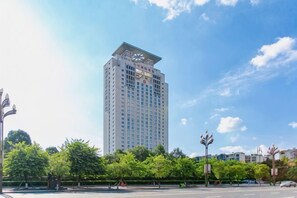 A high-rise building with a modern architectural design, surrounded by greenery and a clear sky. - Eyring Daqian International Hotel (Neijiang City)