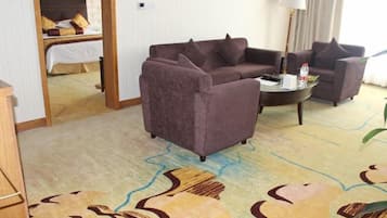 A hotel room with a sofa set, a small round table, and a bed with a headboard.