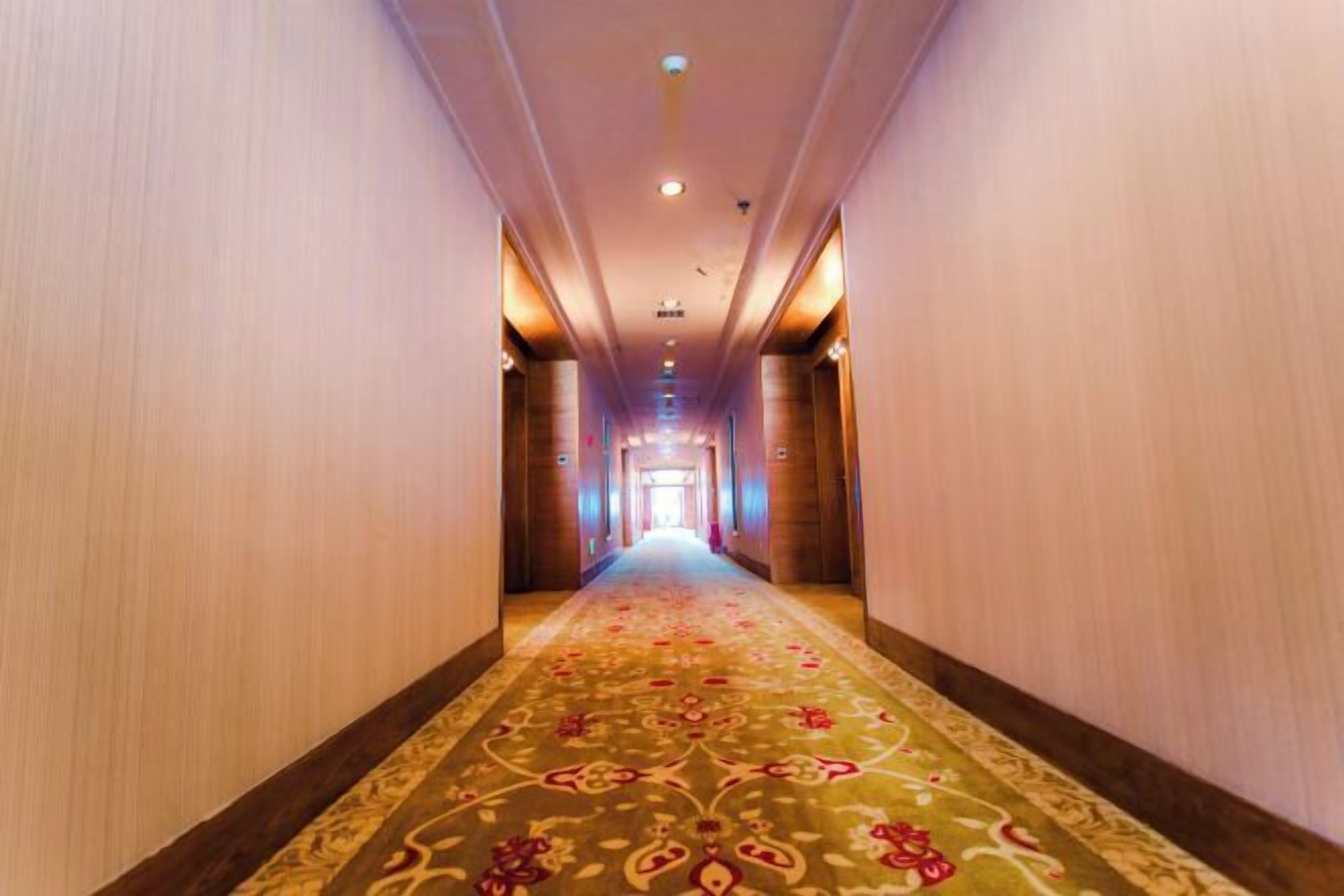 A hotel hallway with a carpeted floor and wooden walls.