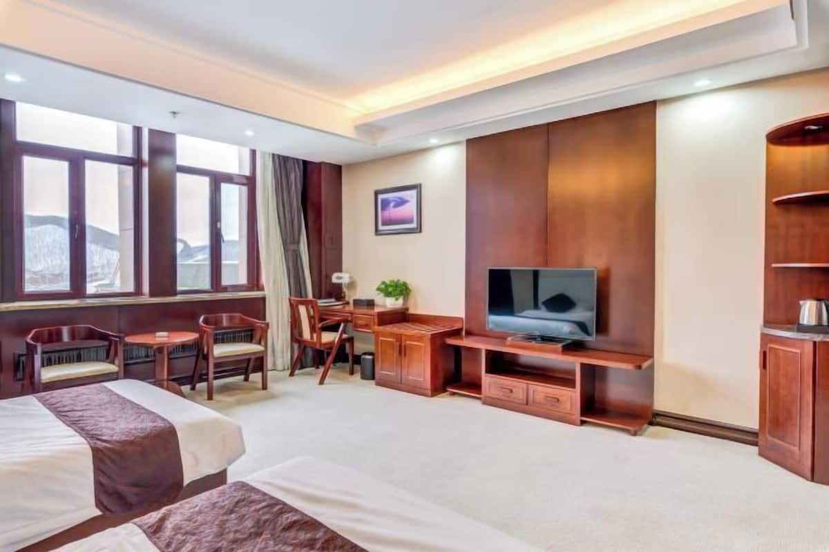 A hotel room with two beds, a TV, a desk, and a chair.