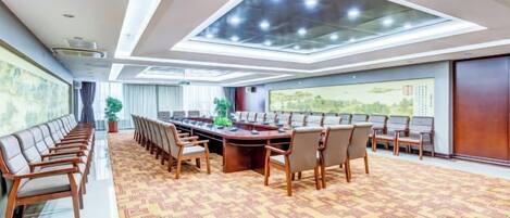A conference room with a long table, chairs, and a patterned carpet.