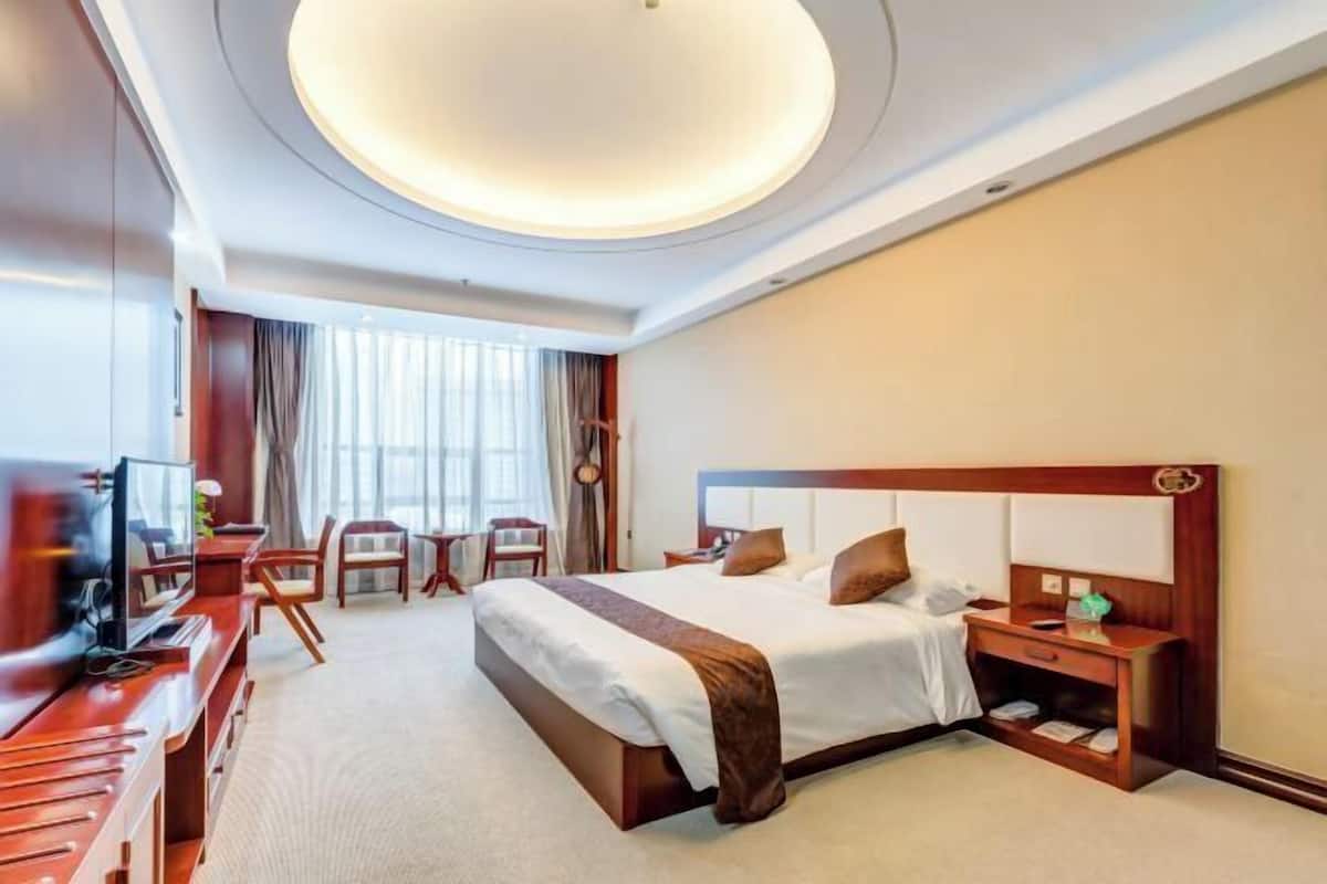 A hotel room with a bed, a TV, a desk, and a chair.