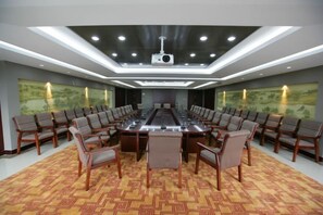 A conference room with a long table, chairs, a projector, and a carpeted floor. - Longyuan Northern Base (Yichun)