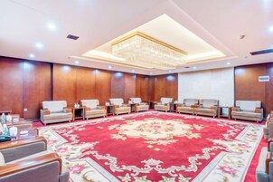 A conference room with a large red carpet, multiple seating arrangements, and a chandelier.