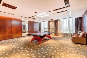 Una habitación con mesa de ping pong, un sofá y una alfombra estampada.