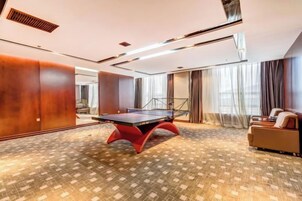 Una habitación con mesa de ping pong, un sofá y una alfombra estampada.