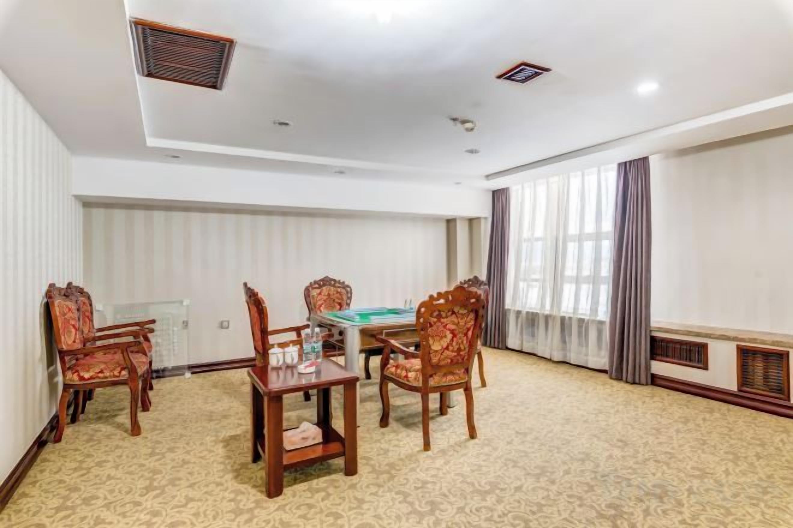 Une salle de conférence équipée d’une table et de chaises, d’une table de billard et d’une grande fenêtre avec des rideaux.
