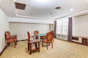 Una sala de conferencias con mesa y sillas, una mesa de billar y un ventanal con cortinas.
