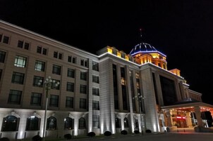 Un edificio grande de varios pisos con una cúpula destacada y una entrada iluminada.