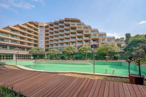 Un hotel con varios pisos, piscina y una terraza de madera.
