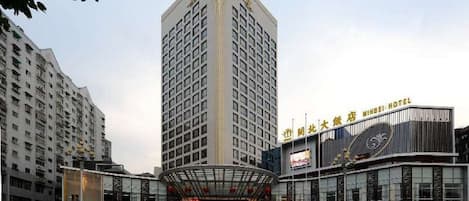 A multi-story hotel with a prominent central tower, a modern glass facade, and a sign indicating it is a hotel.
