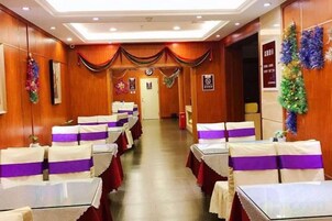 A hotel room with a long corridor, rows of tables with purple sashes, and wooden paneling.