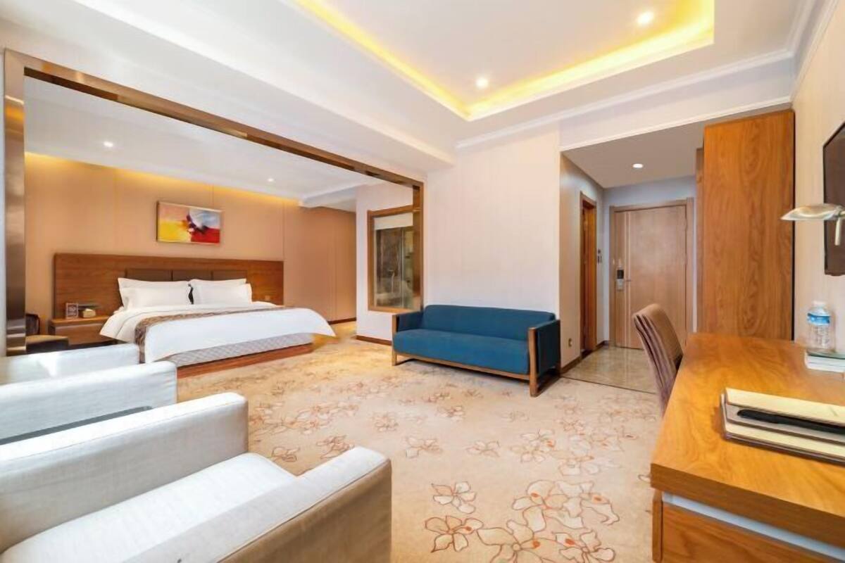 A hotel room with a bed, a sofa, a desk, and a chair.