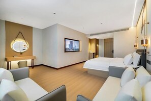 Quarto de hotel moderno com uma cama grande, um sofá, uma escrivaninha e um espelho.