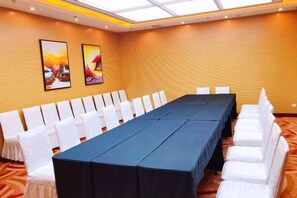 A conference room with a long table, white chairs, and two framed artworks on the wall. - Elong Wanguo Hotel (Liaoyuan Railway Station Traditional Chinese Medicine Hospital) (Liaoyuan)