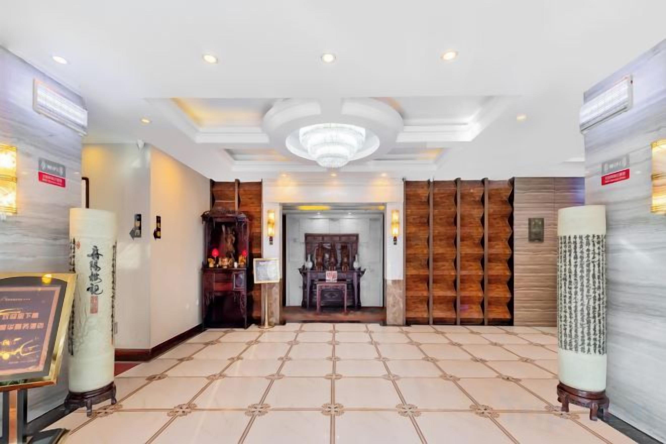 A hotel lobby with a tiled floor, a reception desk, and a wooden wall with a framed picture.