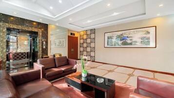 A hotel lobby with leather sofas, a coffee table, and artwork on the walls.