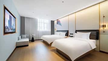 Quarto de hotel moderno com duas camas, um sofá, uma pequena mesa e uma janela grande.