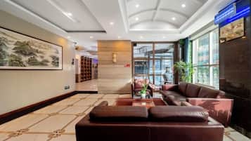 A hotel lobby with a reception desk, seating area, and a large window.