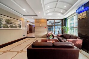 A hotel lobby with a reception desk, seating area, and a large window. - Elong Wanguo Hotel (Liaoyuan Railway Station Traditional Chinese Medicine Hospital) (Liaoyuan)
