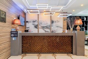 A reception desk with a modern design, featuring a wooden panel and a patterned wall. - Elong Wanguo Hotel (Liaoyuan Railway Station Traditional Chinese Medicine Hospital) (Liaoyuan)