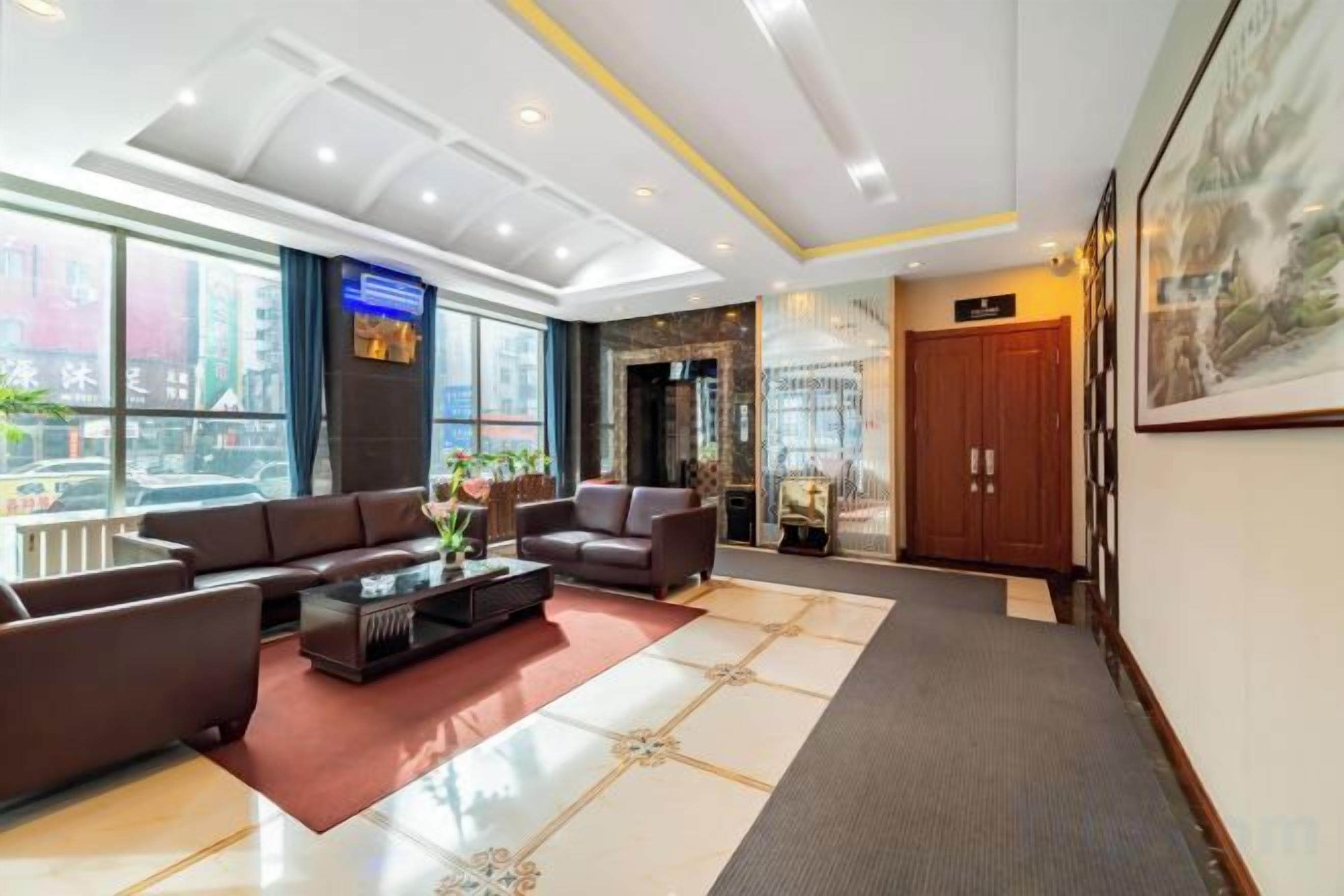Een hotel lobby met een receptiebalie, een zithoek en een groot raam met uitzicht op de stad.