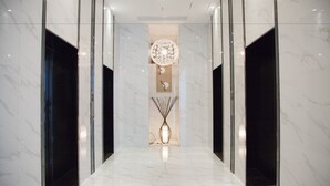 A hallway with a marble floor, a central decorative vase, and a circular wall art piece. - Yuwa Serviced ApartHotel (Foshan)