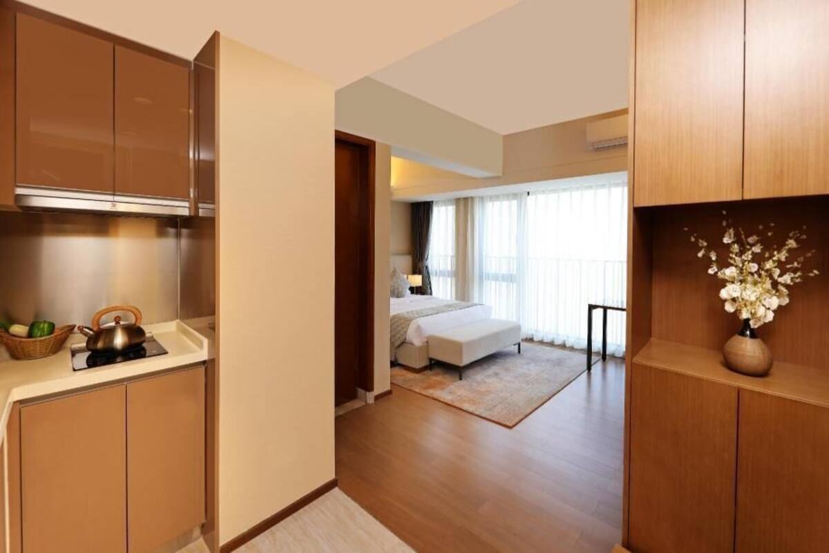 A modern hotel room with a kitchenette, a bed, a bathroom, and a view of the outdoors.