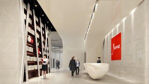 A modern hotel lobby with a sleek design, featuring a large white reception desk, a spacious area with a unique white sculptural element, and a prominent red sign with the hotel name. - Yuwa Serviced ApartHotel (Foshan)
