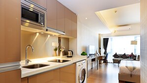 A modern kitchen with a built-in microwave, sink, and washing machine. - Yuwa Serviced ApartHotel (Foshan)