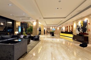 A spacious lobby with a reception desk, seating area, and a large artwork on the wall. - Reethi Rah Hotel (Xiamen)