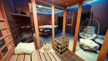 A sauna room with wooden benches, a wooden bench with a towel, a wooden crate, and a hanging chair.
