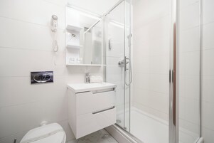 Un bagno moderno con box doccia in vetro, lavandino bianco e water.