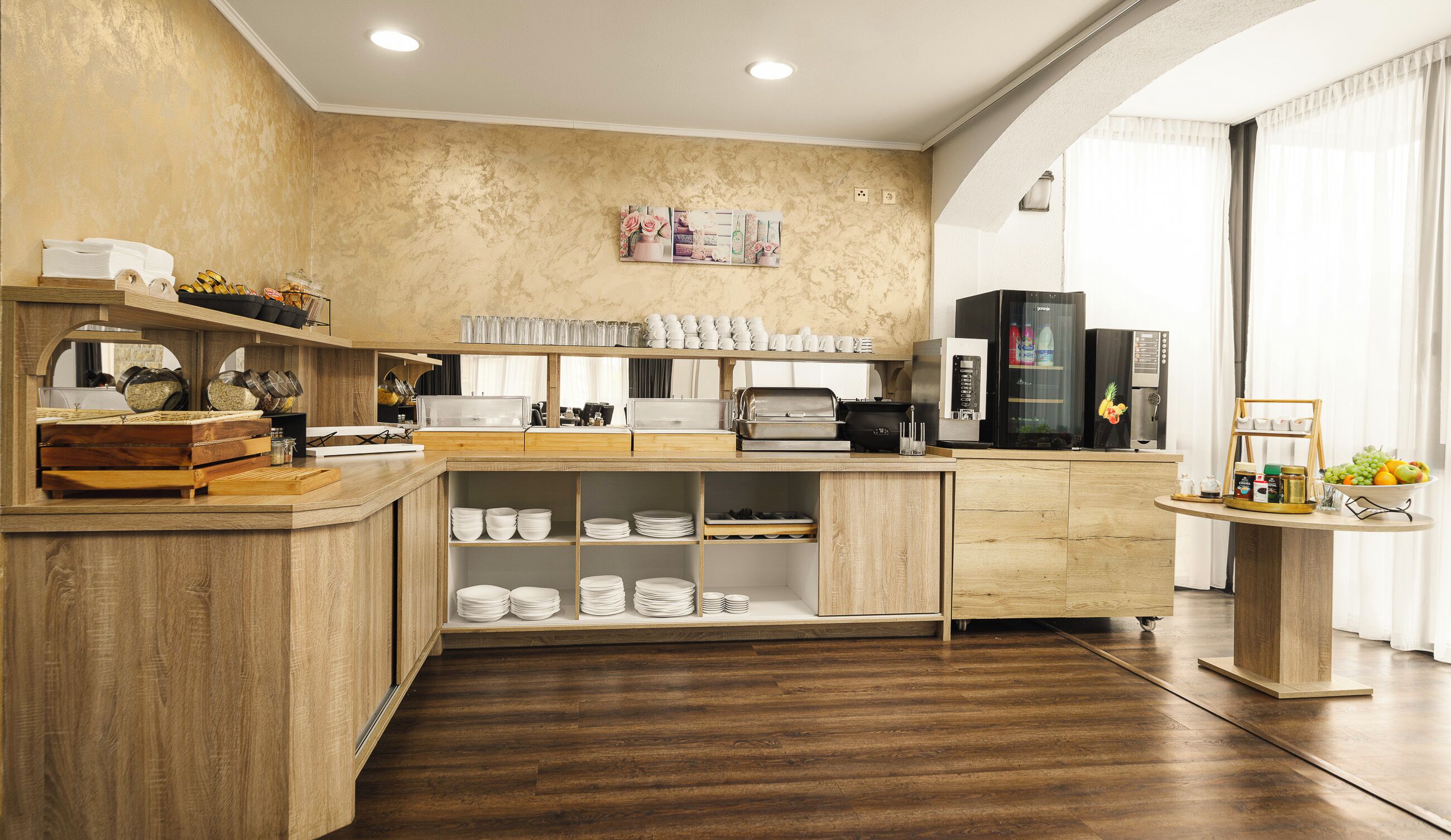 Eine moderne Küche mit Holzschränken, einer Kaffeemaschine und einer Obstschale.