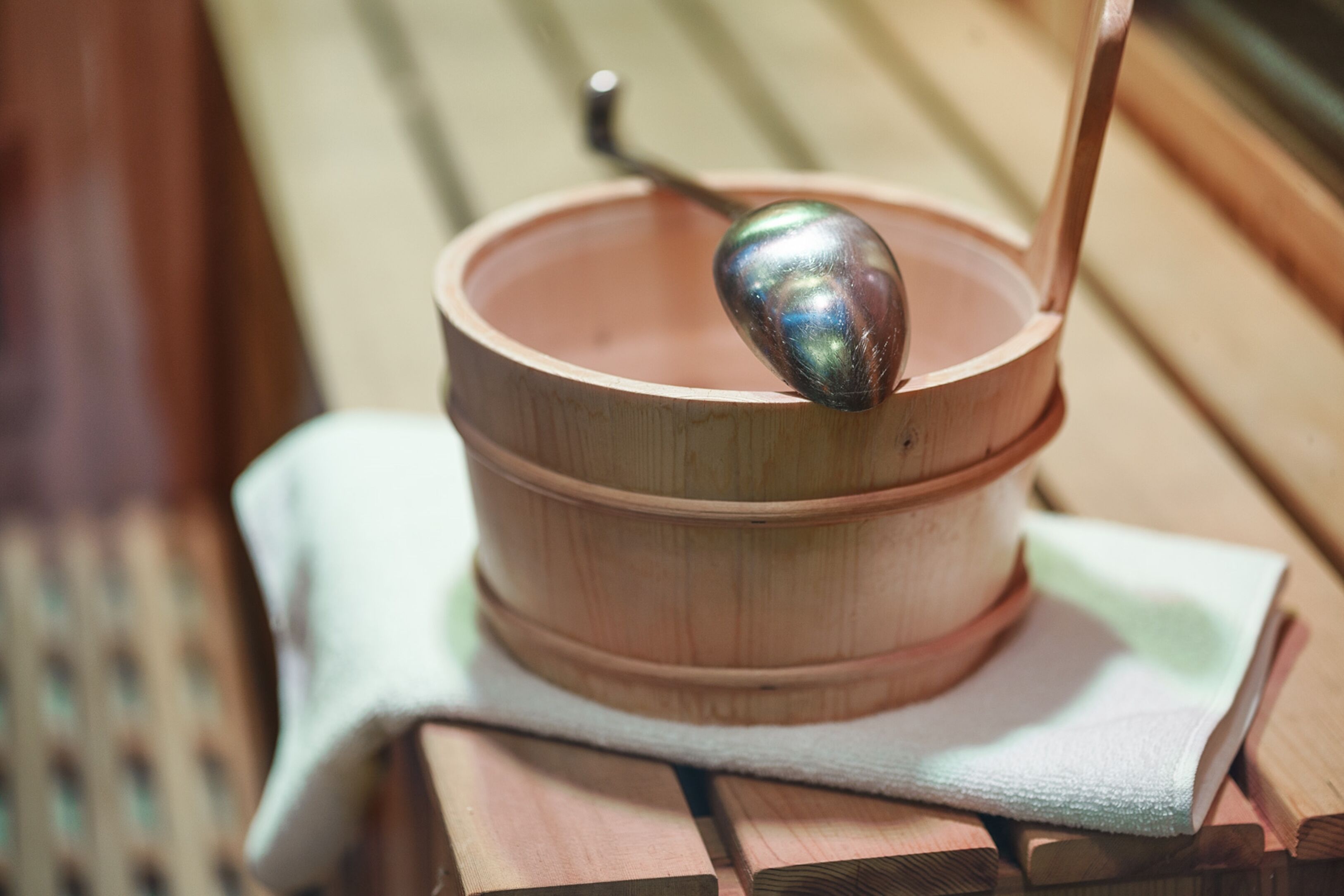 Un contenitore di legno con un cucchiaio all'interno, posizionato su una superficie in legno con un panno sotto.