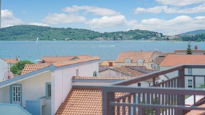 A coastal town with terracotta-roofed buildings, a clear blue sky, and a sailboat on the water. - Hotel Stella Maris (Vodice)